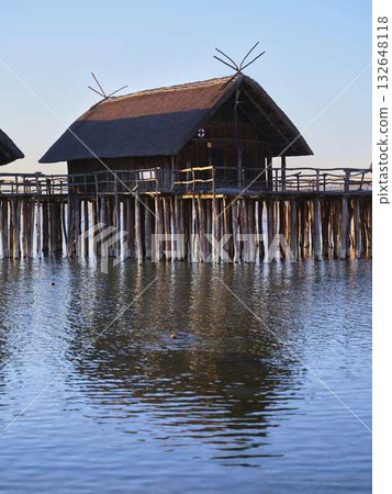 Beautiful wooden cottages on a peaceful lake at sunset reflecting in calm waters Beautiful wooden cottages on a peaceful lake at sunset reflecting in calm waters 132648118