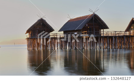Floating wooden houses at dawn with reflections on calm water in a serene coastal location 132648127