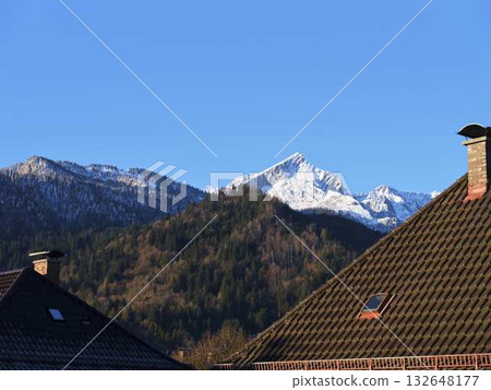 Snow-capped mountain rises over rooftops on a clear day in a tranquil village Snow-capped mountain rises over rooftops on a clear day in a tranquil village 132648177