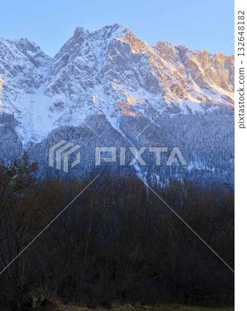 Snow-capped mountain peaks illuminated by the golden light during the early morning hours in a serene landscape Snow-capped mountain peaks illuminated by the golden light during the early morning hours in a serene landscape 132648182