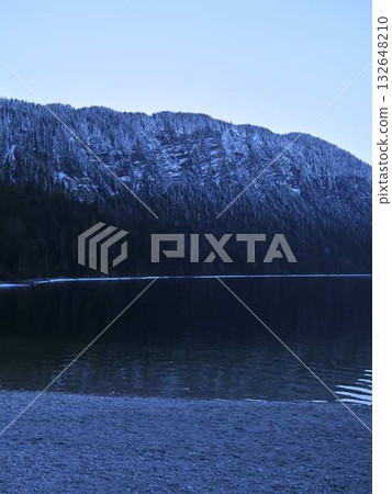 Calm waters reflect snowy mountains during twilight at a serene lakeside location Calm waters reflect snowy mountains during twilight at a serene lakeside location 132648210