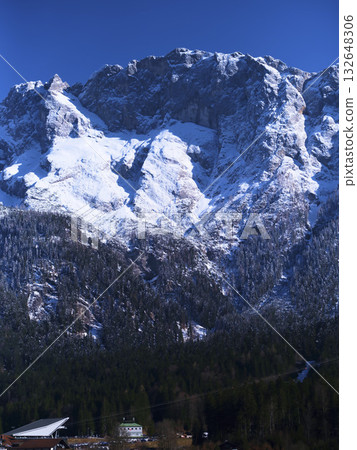 Majestic snow-capped mountains rise above a lush valley in winter light near an alpine village 132648306