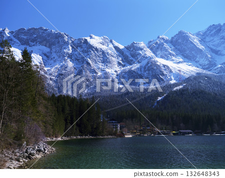 Breathtaking alpine landscape showcasing snow-capped mountains and a serene lake in winter 132648343