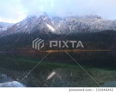Snow-capped mountains reflect in tranquil lake during early morning hours in a serene outdoor landscape Snow-capped mountains reflect in tranquil lake during early morning hours in a serene outdoor landscape 132648442