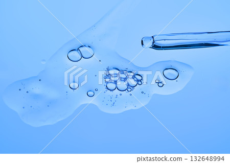 Dropper dropper with cosmetic serum on a blue background. Dropper dropper with cosmetic serum on a blue background. 132648994