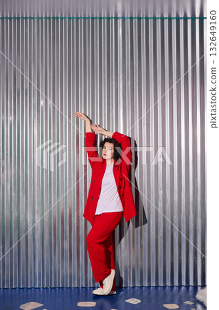 confident woman in red suit demonstrating energetic pose with stylish attitude and bold silhouette 132649160