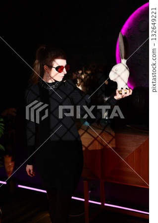 chic woman in lounge bar with rabbit, elegant woman at lounge bar holding playful rabbit prop 132649221
