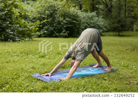 A person practicing yoga in nature, performing Downward Dog Pose for balance and calmness A person practicing yoga in nature, performing Downward Dog Pose for balance and calmness 132649252