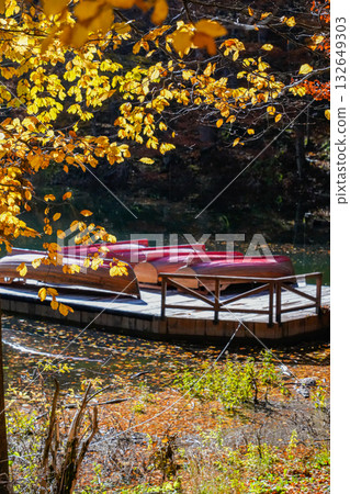 Orange Autumn Leaves by Lake with Boats on Pier Orange Autumn Leaves by Lake with Boats on Pier 132649303