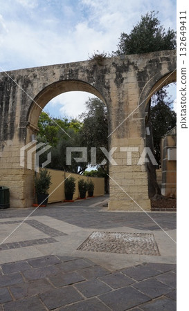 The arches and historic plaques lead you to the walls with a view down to the cannons. Upper Barrakka Gardens are a public garden in Valletta, Malta. 132649411