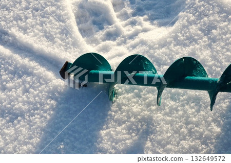 Teal Ice Fishing Auger Drill Blade Resting on Fresh Snow Surface 132649572