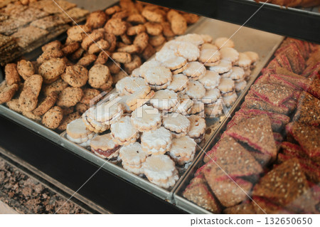 Assortment of cookies and pastries with powdered sugar and seeds in bakery display 132650650