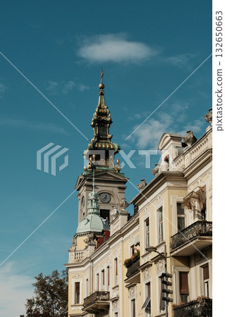 Golden church tower and ornate building facade under blue sky in old Belgrade, Serbia Golden church tower and ornate building facade under blue sky in old Belgrade, Serbia 132650663