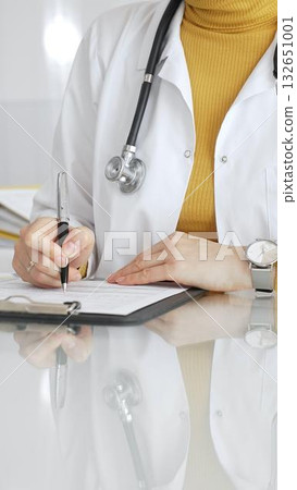 Female physician filling out medical documentation, preparing a diagnosis, or providing healthcare services in a clean, modern clinic. Concept of medicine, healthcare, and science Female physician filling out medical documentation, preparing a diagnosis, or providing healthcare services in a clean, modern clinic. Concept of medicine, healthcare, and science 132651001