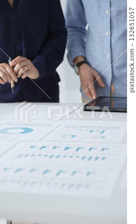 Professional team reviewing financial documents, pointing at charts on desk, collaborating to analyze data and strategize business growth. Business people concept Professional team reviewing financial documents, pointing at charts on desk, collaborating to analyze data and strategize business growth. Business people concept 132651057