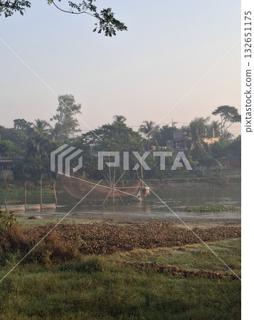 A tranquil rural landscape at dawn, with a misty sky, lush trees, and harvested fields in the foreground A tranquil rural landscape at dawn, with a misty sky, lush trees, and harvested fields in the foreground 132651175