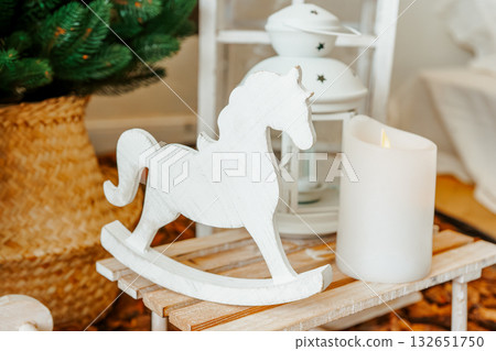 Cozy indoor setting, composition white candle and wooden decorations on Christmas trees background 132651750