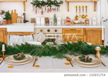 Elegant Christmas holiday table setting with greenery and simple decor on cozy kitchen background 132651754