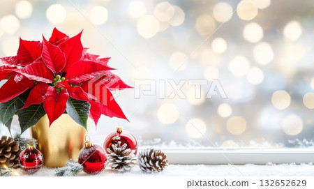 Festive still life with red poinsettia plant, Christmas ornaments, and pine cones on a snowy background 132652629