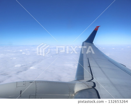Aerial View From Airplane Wing Over Clouds With Blue Sky And Wingtip Glide Sunlight Bright 132653264