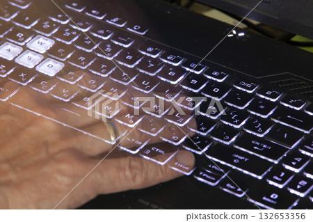 Close-up of a hand pressing the Home key on a black laptop keyboard with white backlighting. The keyboard contains Russian and English characters. The image conveys the atmosphere of night work. Close-up of a hand pressing the Home key on a black laptop keyboard with white backlighting. The keyboard contains Russian and English characters. The image conveys the atmosphere of night work. 132653356