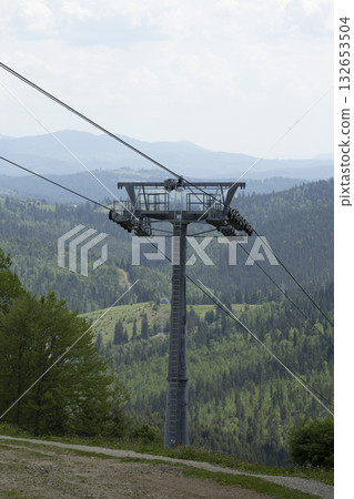 Cable car supports, chairlift hangs over a green mountain valley Cable car supports, chairlift hangs over a green mountain valley 132653504