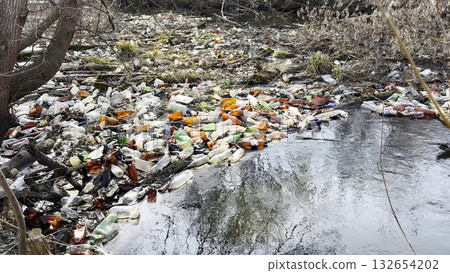 Dirty river is polluted with many plastic bottles. A lot of trash is dumped in open and freely available places at nature. Global environmental pollution problem. Concept of ecological disaster 132654202