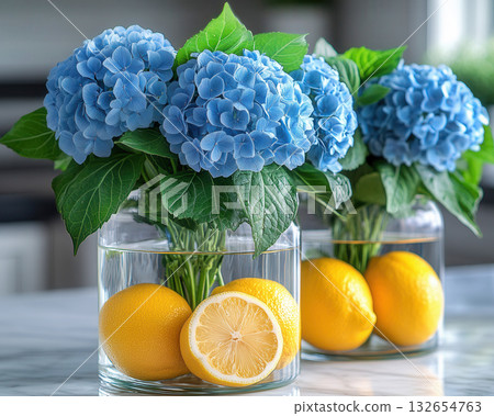 Glass vases hold vibrant blue hydrangeas and fresh lemons, citrus freshness creating fresh, bright, and creative kitchen 132654763