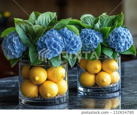 Glass vases hold vibrant blue hydrangeas and fresh lemons, citrus freshness creating fresh, bright, and creative kitchen 132654780