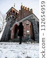 Person in black coat standing before an old brick church on a snowy day. Concept of solitude, faith, history, and reflection in winter atmosphere 132654959