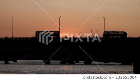 London red buses crossing bridge at sunset with tourists walking 132655004