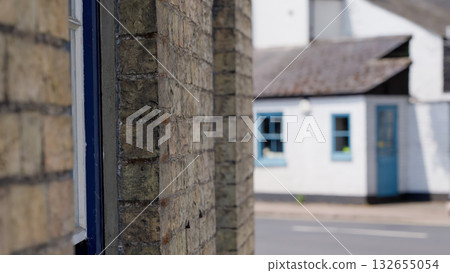Brick wall framing a blurred view of a small house in Cambridge, UK 132655054