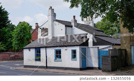 Traditional white pub showing weathered sign and blue doors in Cambridge, UK 132655056
