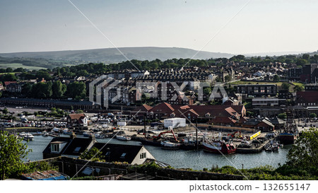 Whitby harbor with boats and North York Moors National Park rising in the background Whitby harbor with boats and North York Moors National Park rising in the background 132655147