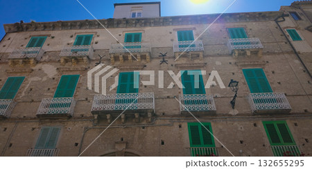 Sun shining on traditional building with green shutters in Tropea, Italy Sun shining on traditional building with green shutters in Tropea, Italy 132655295