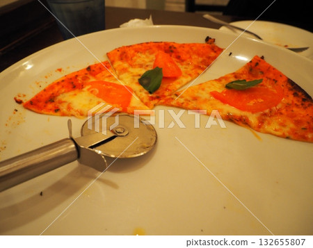 The night of a small amount of pizza left on a white plate and a pizza cutter that had outlived its usefulness The night of a small amount of pizza left on a white plate and a pizza cutter that had outlived its usefulness 132655807