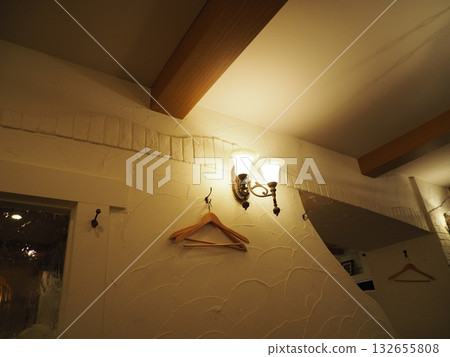 The interior features bracket lighting that gently illuminates the plaster-like walls and wooden hangers. The interior features bracket lighting that gently illuminates the plaster-like walls and wooden hangers. 132655808