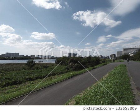 一條河畔自行車道，俯瞰著平靜的多摩川河水，藍天白雲籠罩。 132655809