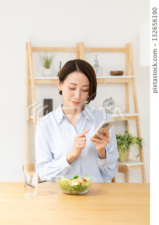A woman eating while watching a smartphone A woman eating while watching a smartphone 132656190