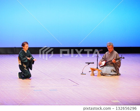 三味線演奏結束後，觀眾鞠躬致謝：舞台上一片寂靜，藍色背景映襯著靜謐的迴響。 132656296