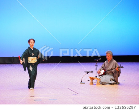 Dancer in traditional Japanese clothing holding a fan: Shamisen music and a blue sky-colored stage 132656297