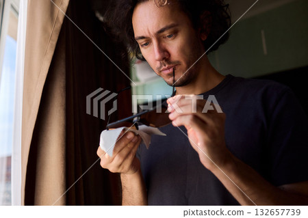 Sunlit window showcases delicate craft, Hands skillfully fold paper into intricate boat shape, Artistic paper boat reflects craftsmanship illuminated by sunlight 132657739