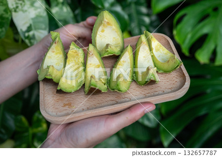 Cropped shot view of someone holding pieces of Avocado fruit. Cropped shot view of someone holding pieces of Avocado fruit. 132657787