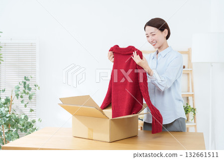 一位女士正在把衣服放進紙箱裡 132661511