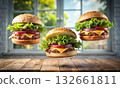 Three appetizing cheeseburgers floating midair above a wooden surface 132661811