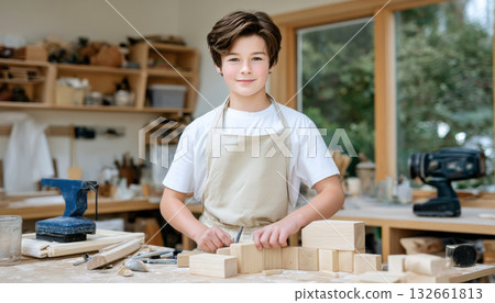 Young craftsperson in small business woodshop smiling while shaping wooden blocks with hand tools and natural light 132661813