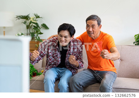 Exciting Sports Moment. Grandfather and grandson cheering while watching TV. 132662576