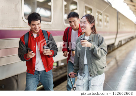 Travel Companions. Friends walking together at a train station with coffee. 132662608