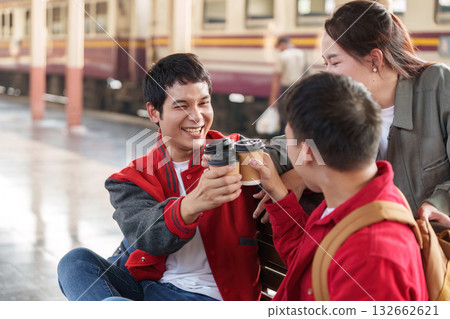 Celebratory Moment. Young friends toasting with coffee cups at a train station. Celebratory Moment. Young friends toasting with coffee cups at a train station. 132662621