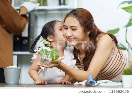 Family Gardening and Sustainability. A mother and daughter bonding over plant care at home. 132662666